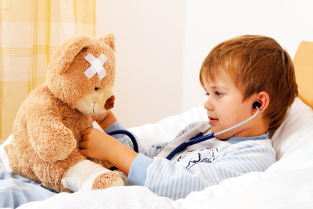 Ein Krankes Kind untersucht Teddy mit Stethoskop